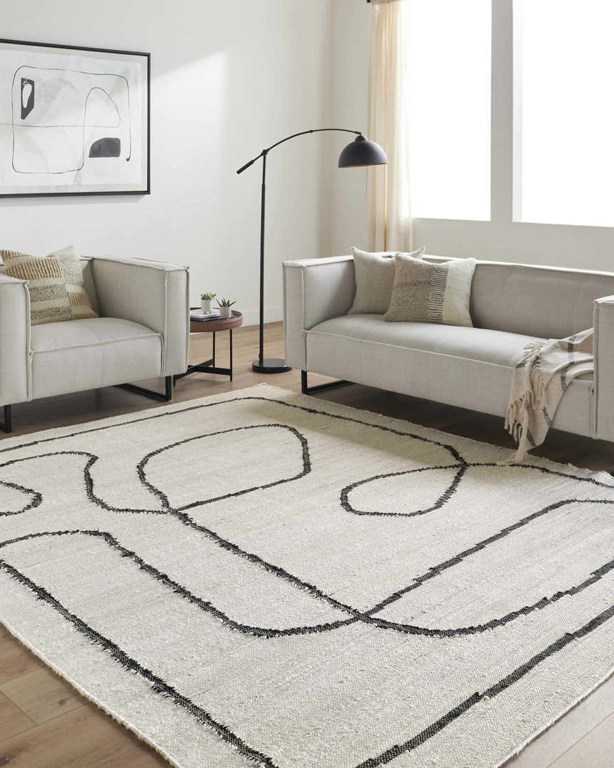 Living room with neutral sofas and a cream Shael Jute Area Rug with a black abstract line design. Roomscene-Rectangle