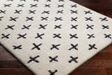 Close-up of the Bede Washable Area Rug. Beige shag rug with a charcoal geometric X pattern. Transitional style. Corner