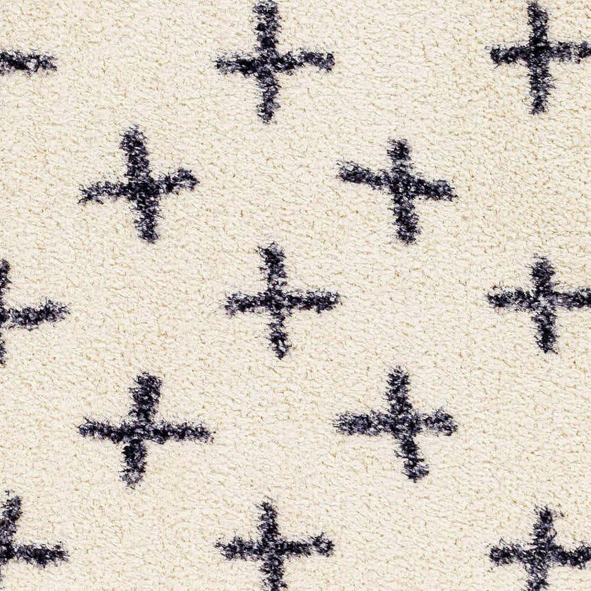 Close-up of the Bede Washable Area Rug. Beige shag rug with a charcoal plus sign geometric pattern. Soft, textured rug detail. Swatch