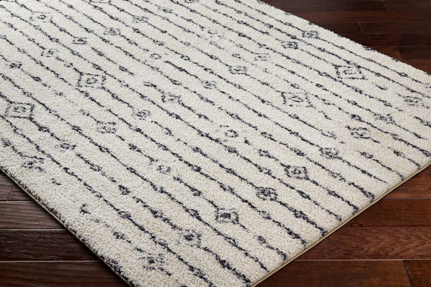 Close-up of the Demi Beige Washable Area Rug, featuring a striped bohemian pattern on a soft, textured pile. Corner