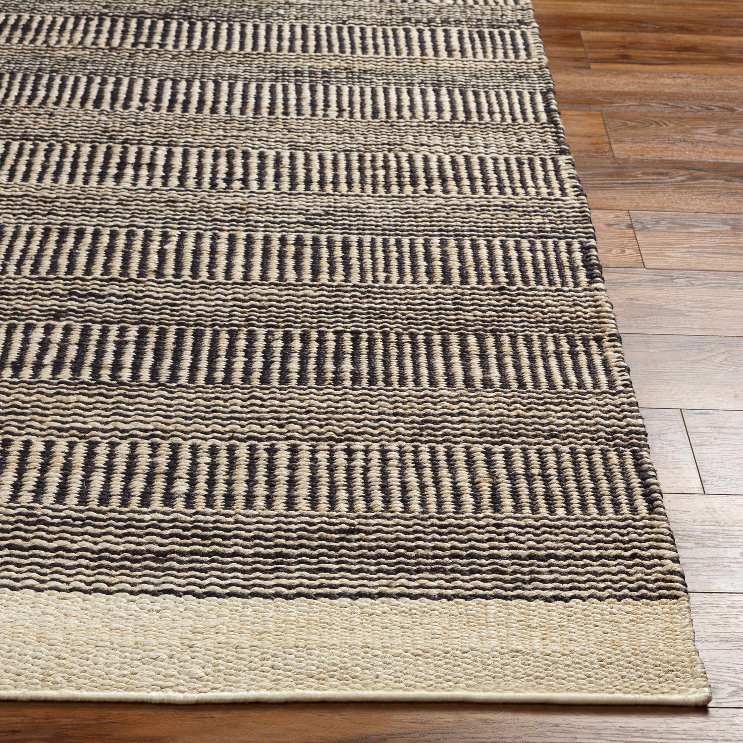 Close-up of the Black Elle Area Rug showing its hand-woven jute texture and geometric black and beige stripes. Front