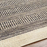 Close-up of the hand-woven Black Elle Area Rug. Jute rug with a geometric pattern in beige and black. Texture