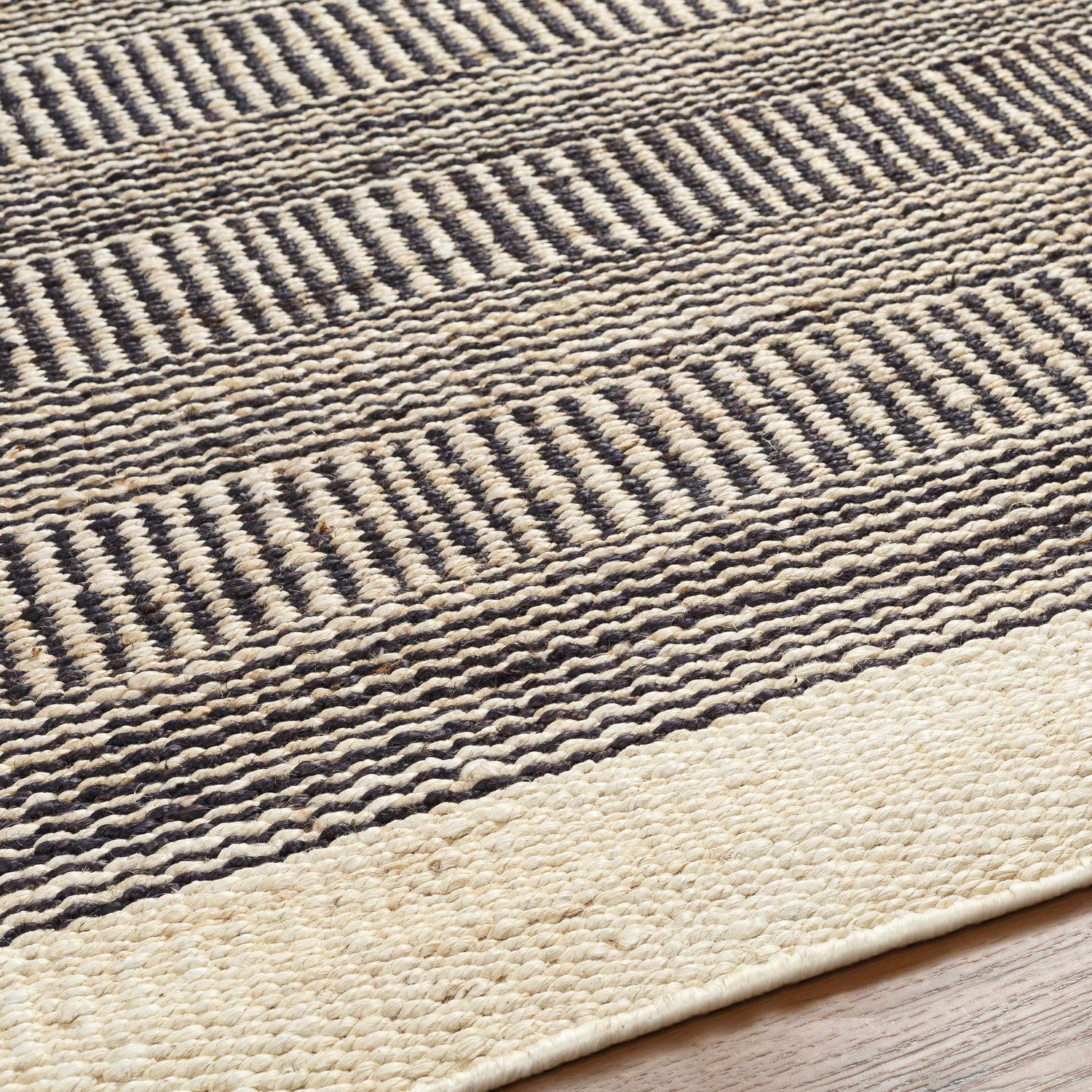 Close-up of the hand-woven Black Elle Area Rug. Jute rug with a geometric pattern in beige and black. Texture