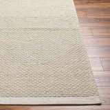 Close-up of the hand-woven Cream Emlen Area Rug showing its textured, geometric pattern and neutral color on a wood floor. Front