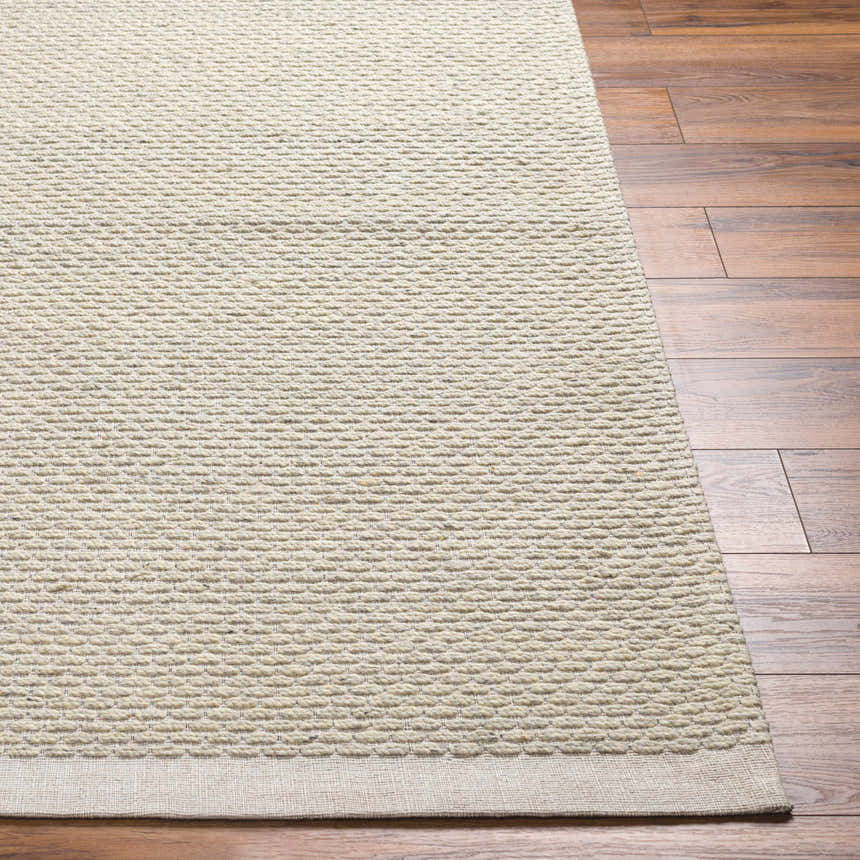 Close-up of the hand-woven Cream Emlen Area Rug showing its textured, geometric pattern and neutral color on a wood floor. Front