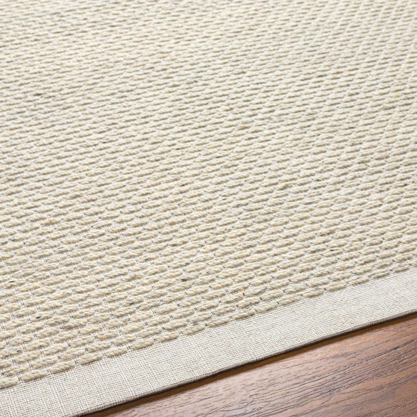 Close-up of the hand-woven Cream Emlen Area Rug showing the neutral color, textured wool, and subtle pattern. Texture