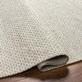 Close-up of the Light Brown Emlen Area Rug showing its hand woven texture and neutral cream and brown color palette. Fold
