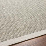 Close-up of the hand woven Light Brown Emlen Area Rug showing its textured wool design and cream color on a wood floor. Texture