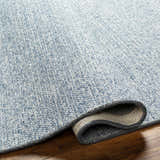 Close up of the hand woven texture of the Alyra Light Blue Solid Area Rug. Fold