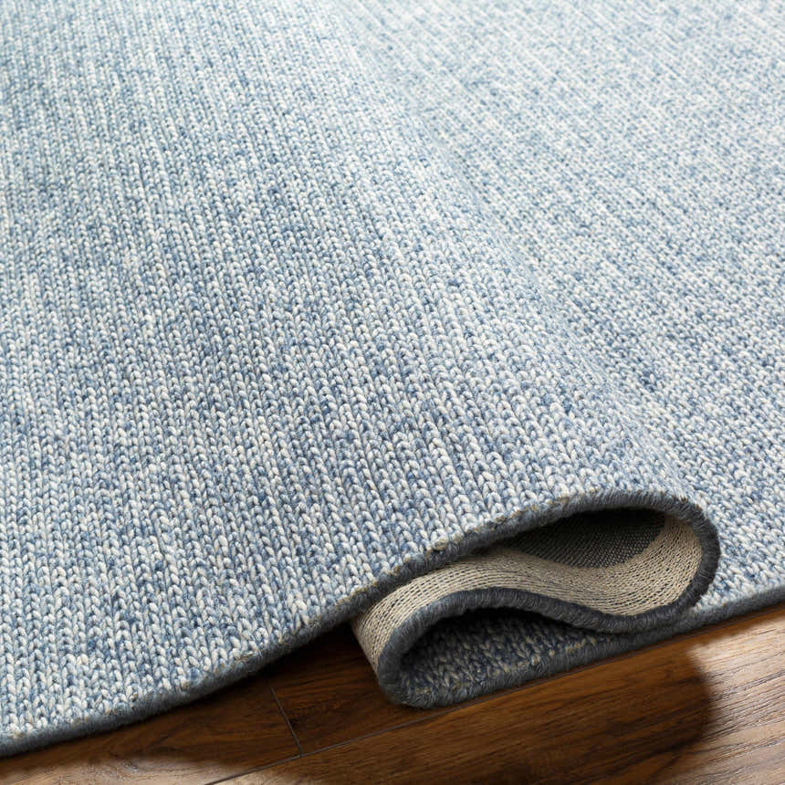 Close up of the hand woven texture of the Alyra Light Blue Solid Area Rug. Fold