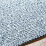 Close-up of the hand woven Alyra Light Blue Solid Area Rug, showing wool texture and subtle color variations. Texture