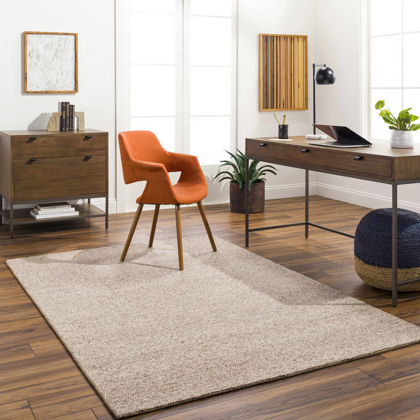 Bright home office with Alyra Tan Solid Area Rug, wood desk and cabinet, orange chair, and plants. Roomscene-Rectangle
