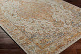 Close-up of Aman Beige Area Rug showing traditional floral pattern with brick red, navy, and sage accents on dark hardwood floor. Corner