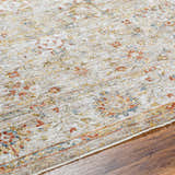 Close up of the Duong Beige Textured Rug with Fringes showing brick red, blue, and mustard floral pattern on a beige background. Texture