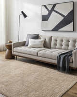 Living room scene with a tan sofa and the Kahua Tan Area Rug adding warmth to the space. Roomscene-Rectangle