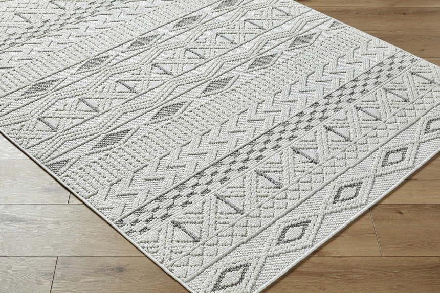 Close-up of the Sokka Area Rug: cream and light gray geometric pattern, machine woven texture. Contemporary style. Corner