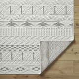 Close-up of the Sokka Area Rug showing its cream, ivory, and light gray contemporary geometric pattern and woven texture. Fold