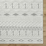 Close-up of the Sokka Area Rug, a cream and light gray polyester rug with a contemporary geometric pattern. Corner