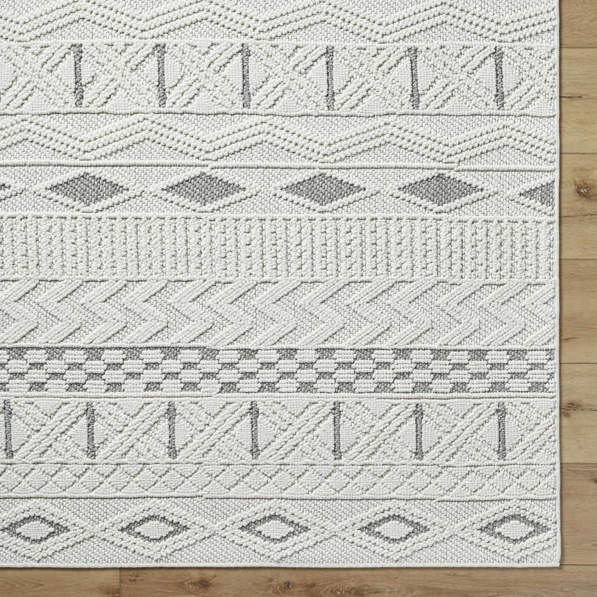 Close-up of the Sokka Area Rug, a cream and light gray polyester rug with a contemporary geometric pattern. Corner