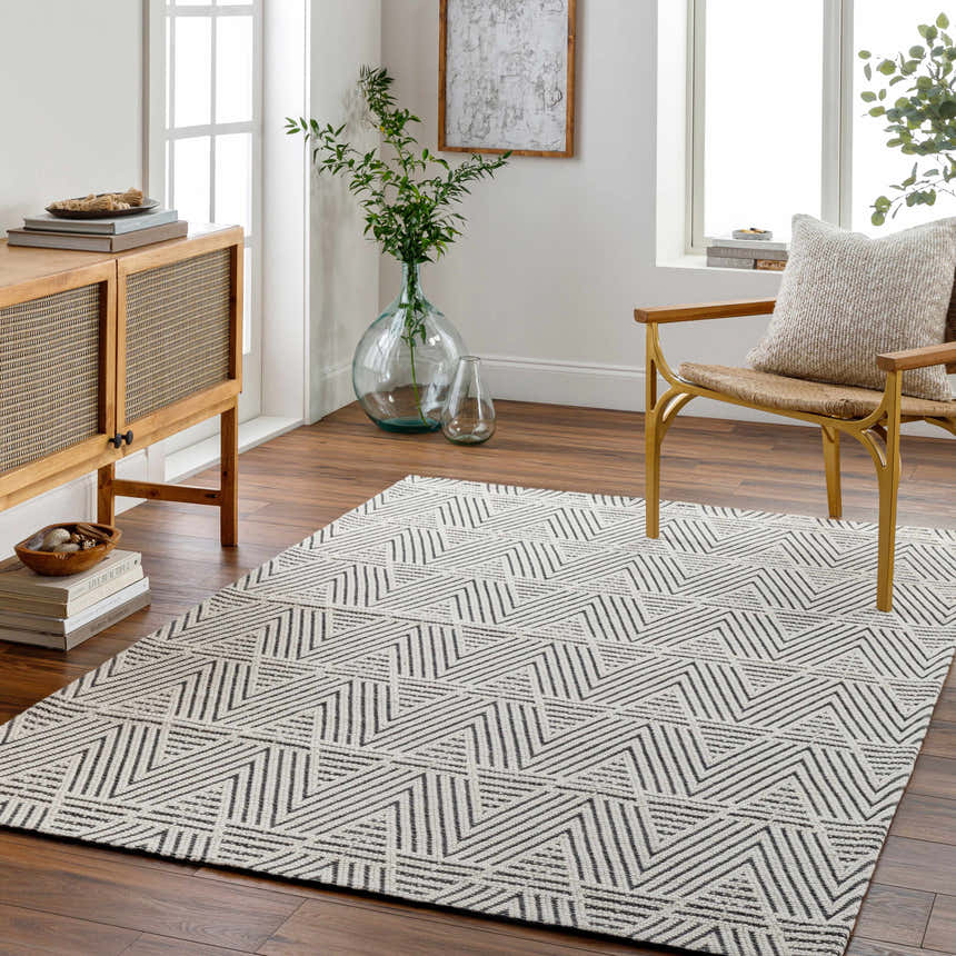 Living room with a Dawid Wool Area Rug, wood cabinet, chair, and geometric black and off-white pattern. Roomscene-Rectangle