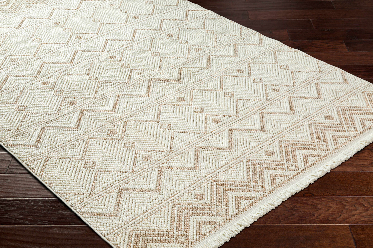 Close-up of the Armen Area Rug, a beige and cream rug with a geometric pattern on dark wood floors. Corner