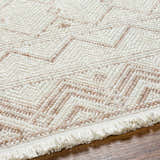 Close up of the Armen Area Rug showing its beige and cream zig-zag pattern and fringed edge. Texture
