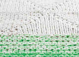 Close-up of hand-woven Snyder Area Carpet rug, showing green and off-white textures and patterns. Styleshot