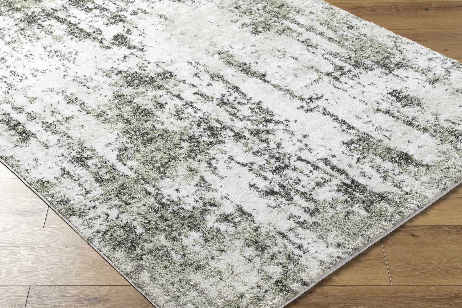 Close up of the light gray Omari Area Rug showing its abstract pattern and soft texture on wood floor. Corner