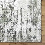 Close-up of the light gray Omari Area Rug showing its contemporary abstract pattern and soft texture on a wood floor. Corner