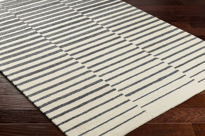 Close up of the Gawel Charcoal Area Rug showing its beige and charcoal striped pattern and hand-tufted texture. Corner