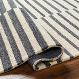 Close-up of the Gawel Charcoal Area Rug showing its beige and charcoal stripes and hand-tufted texture. Fold