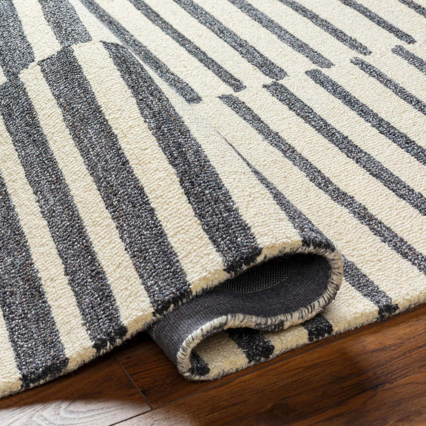 Close-up of the Gawel Charcoal Area Rug showing its beige and charcoal stripes and hand-tufted texture. Fold