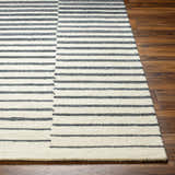 Close-up of the Gawel Charcoal Area Rug featuring a striped pattern in charcoal, beige, and wool texture on wood floors. Front