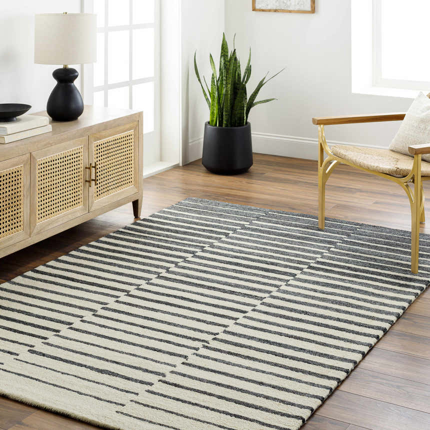 Living room scene with a Gawel Charcoal Area Rug, wood cabinet, gold chair, and potted plant. Roomscene-Rectangle