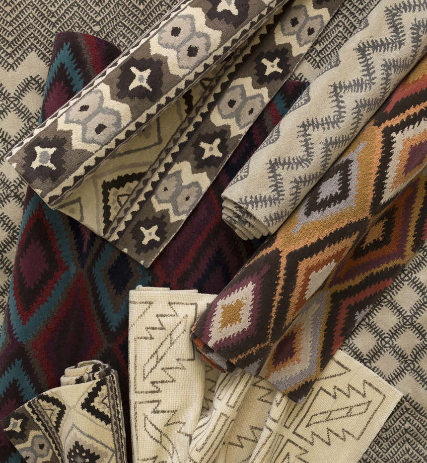 Close-up of rolled Pawhuska Area Rugs. Wool rugs in charcoal, peach, and traditional farmhouse patterns. Styleshot