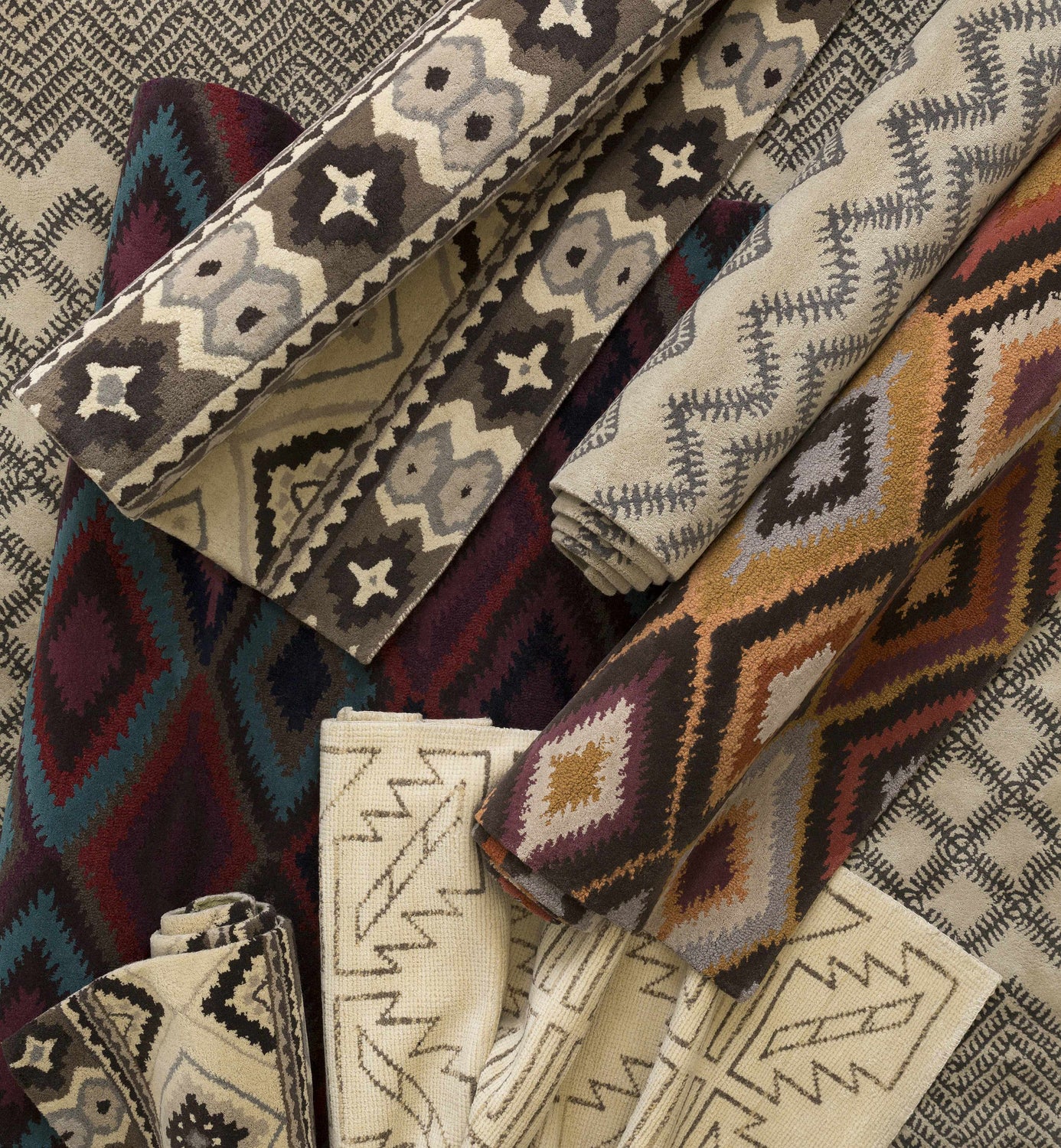 Close-up of rolled Pawhuska Area Rugs. Wool rugs in charcoal, peach, and traditional farmhouse patterns. Styleshot