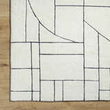 Close-up of the Fusao Rose Cream Area Rug. Beige wool rug with a contemporary geometric pattern in black. Hand-tufted texture. Swatch