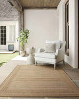 Covered patio with a beige Freja Flatweave Faux Jute Rug, white chair, and stone side table. Roomscene-Rectangle