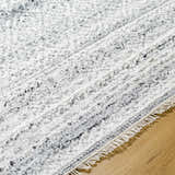 Close-up of the Gray Eldad Area Rug showing its plush texture, fringed edge, and black, silver, and white colors. Texture