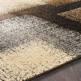 Close-up of the Spraggs Area Rug, showing its contemporary block pattern in black, charcoal, brown, gray, and beige tones. Texture