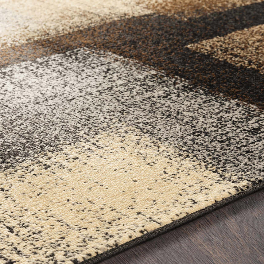 Close-up of the Spraggs Area Rug, showing its contemporary block pattern in black, charcoal, brown, gray, and beige tones. Texture