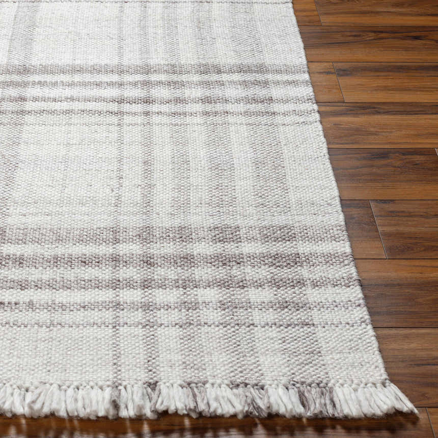 Close-up of the hand-woven Inara Plaid Area Rug with gray and light gray tones, showing the texture and fringe detail. Front