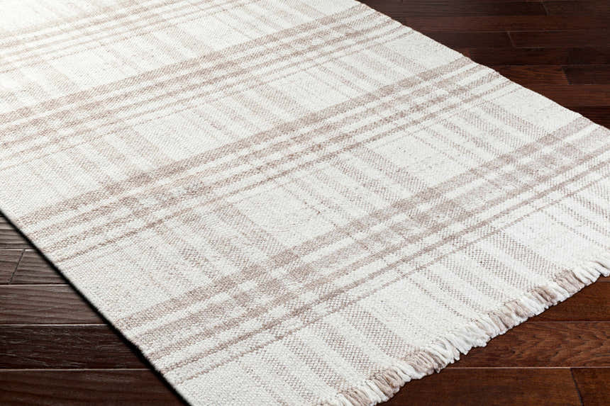 Close-up of the Inara Light Brown Plaid Hand Woven Area Rug on a dark wood floor. Beige and brown plaid pattern. Corner