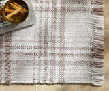 Close-up of the Inara Light Brown Plaid Hand Woven Area Rug, showing the beige and brown pattern and textured fringe. Styleshot
