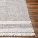 Close-up of the hand-woven Loic Light Brown Area Rug showing its texture, striped pattern, and fringe detail on wood floors. Front