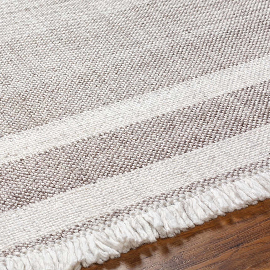Close-up of the hand-woven Loic Light Brown Area Rug with light brown stripes and white fringe detail. Texture
