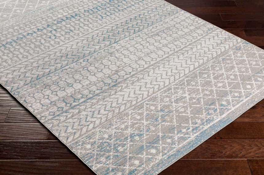 Close-up of the Tambac Blue & Gray Washable Area Rug showing its contemporary geometric pattern and soft blue accents. Corner