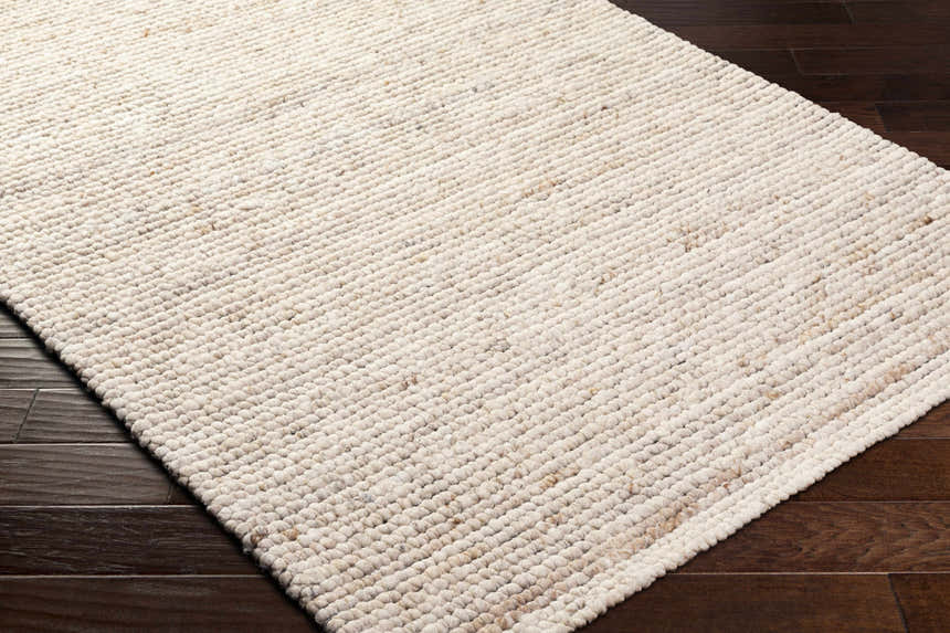 Close-up of the hand-woven Olisa Cream Wool Area Rug showing its beige color and textured, looped design. Corner