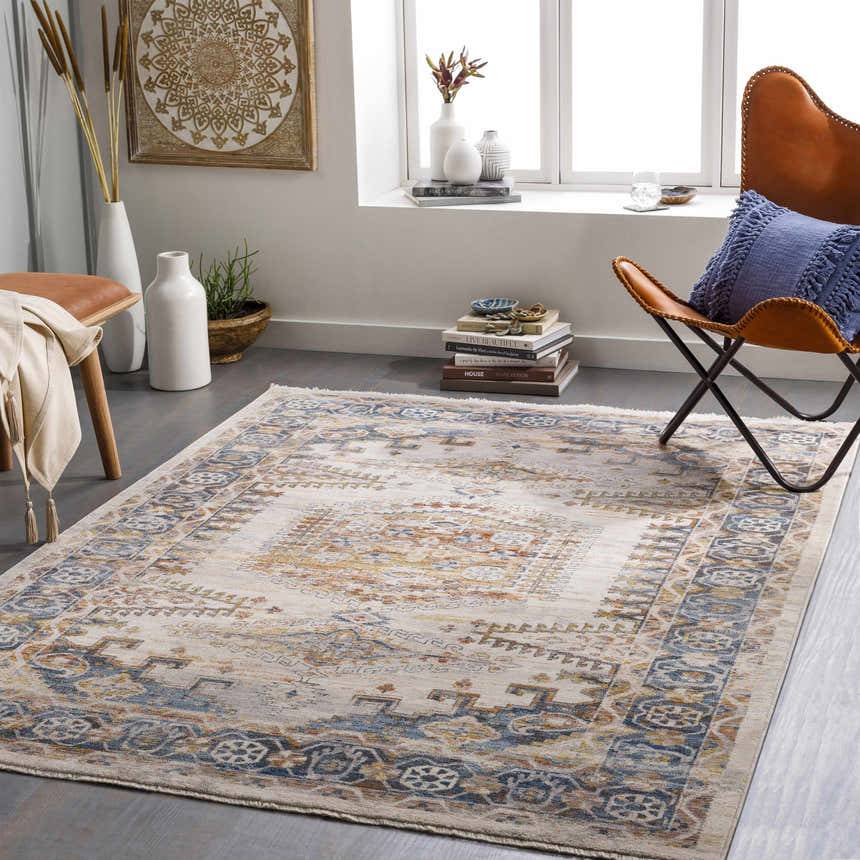 Living room scene with a traditional Espy Area Rug in brick red, burnt orange, and blue tones, styled with a leather chair and modern decor. Roomscene-Rectangle