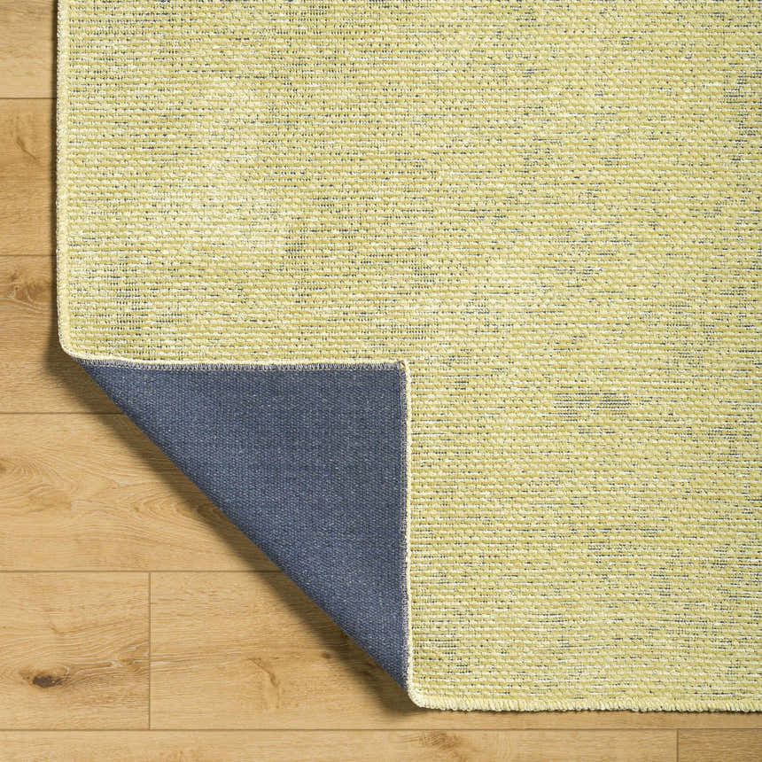 Close-up of the Isako Solid Lime Washable Area Rug showing the textured weave and the blue backing. Fold